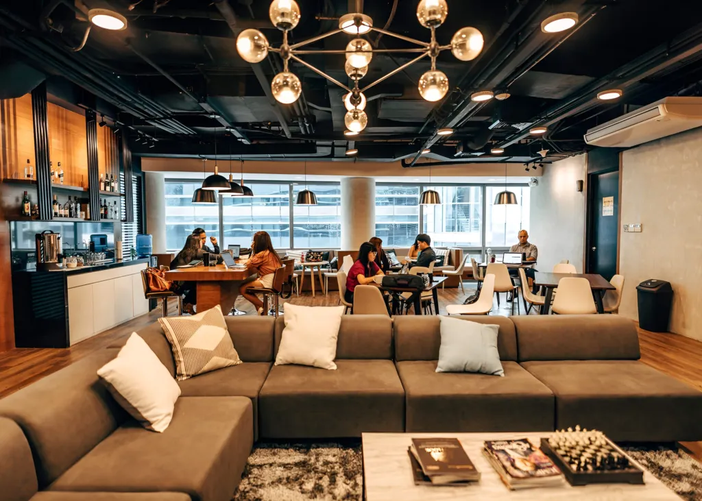 Members working at a long communal table at Acceler8 Rockwell, under warm pendant lighting